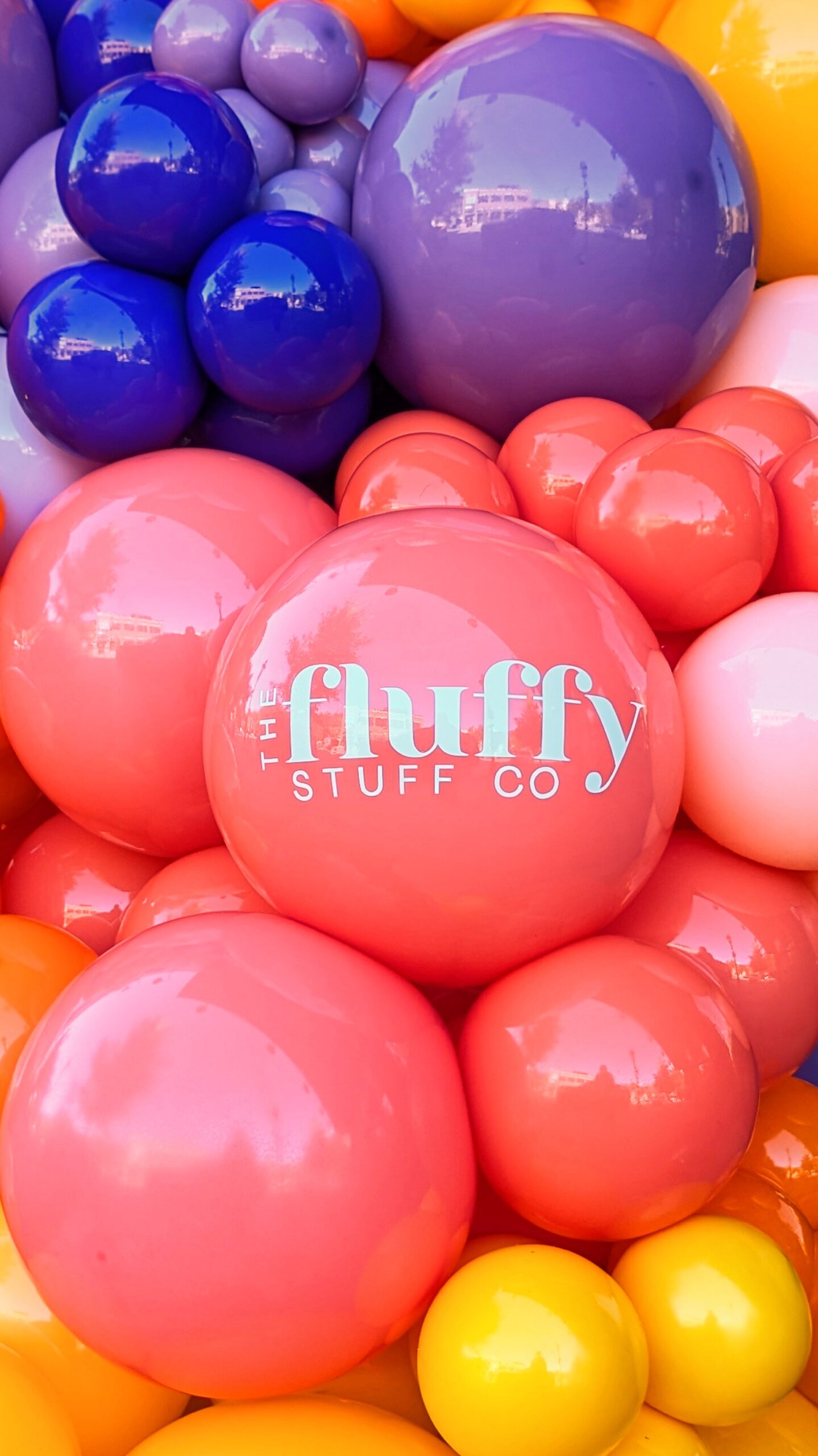 The Fluffy Stuff logo in white on a variety of colorful balloons in pink, red, yellow, blue, and purple