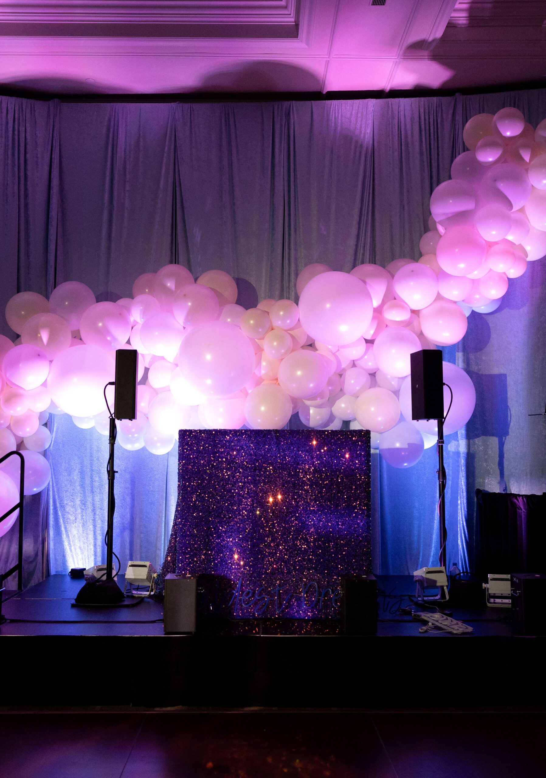 dark stage illuminated with glowing white balloons and a glittery black cloth